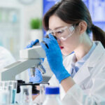 Female scientist examining a sample under a microscope in a laboratory