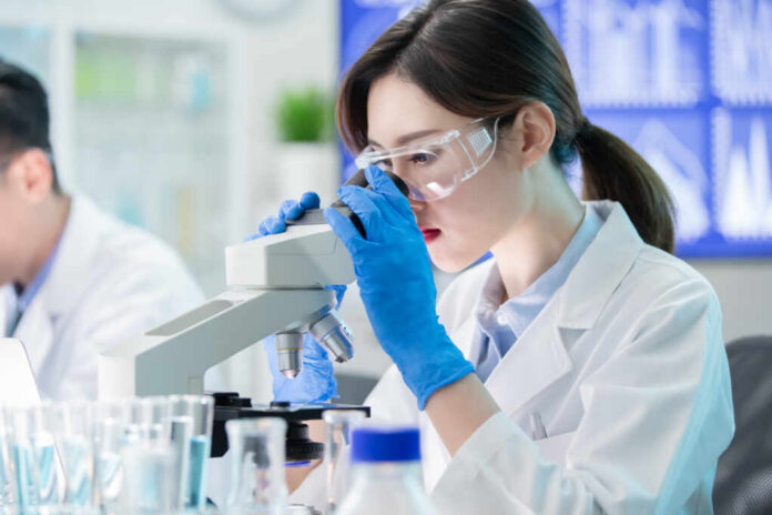 Female scientist examining a sample under a microscope in a laboratory