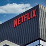 Close-up of the Netflix logo on a modern building against a blue sky