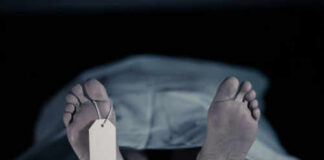 Feet with tag under white sheet in morgue