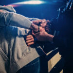 Police officer handcuffing person near a car