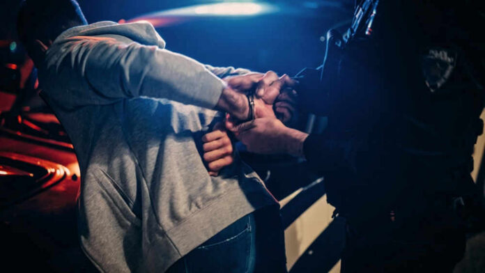 Police officer handcuffing person near a car