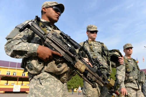 Soldiers in uniform holding weapons outdoors on sunny day