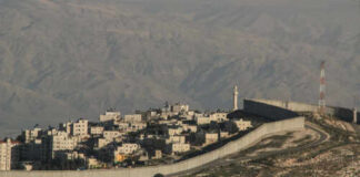 A view of a residential area bordered by a separation barrier in a mountainous region
