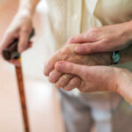 Two hands clasped together, one elderly and one younger, symbolizing support
