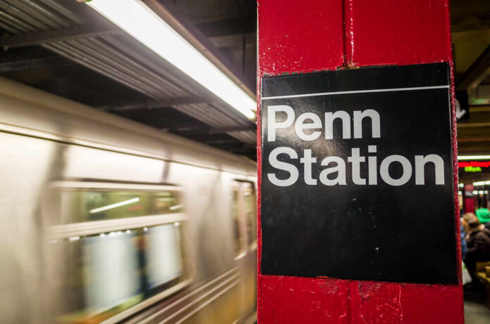 shutterstock_176536292.jpg Sign for Penn Station at a subway platform with a moving train in the background