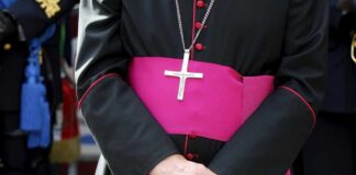 A religious figure in ceremonial attire with a cross necklace