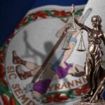 Bronze statue of Lady Justice in front of the Virginia state flag