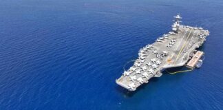 Aerial view of an aircraft carrier in the ocean with military jets on deck