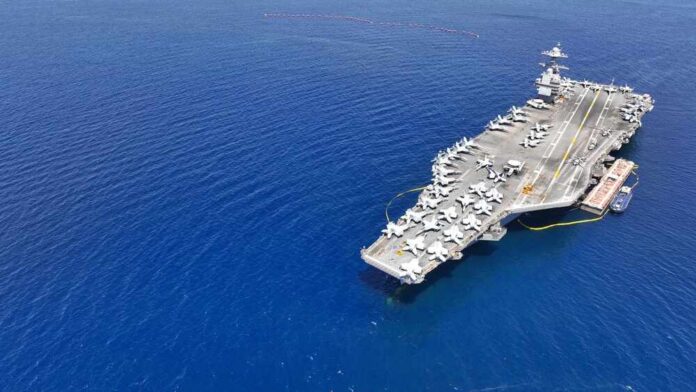 Aerial view of an aircraft carrier in the ocean with military jets on deck