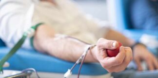 A person donating blood while holding a stress ball