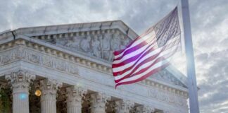 The Supreme Court building with an American flag waving in front