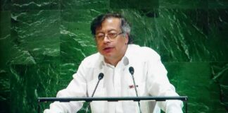 A speaker in a white shirt addressing an audience at a podium