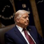 Trump’s SHOCKING Move: 100-Year Law Suspended A political figure sitting with a serious expression in a formal setting