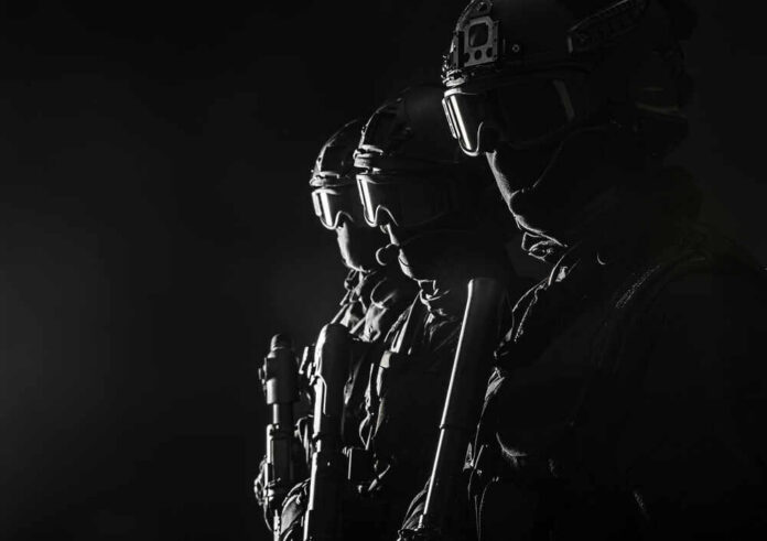 shutterstock_405746488.jpg Silhouetted tactical team members in uniform with weapons