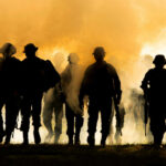AI-Driven Warfare: Silicon Valley’s Dark Turn Silhouettes of soldiers walking through smoke at sunset