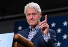 Man in suit gesturing during speech with stars backdrop