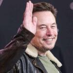Man in leather jacket smiling and waving