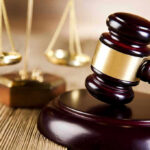 Wooden gavel and scales of justice on table
