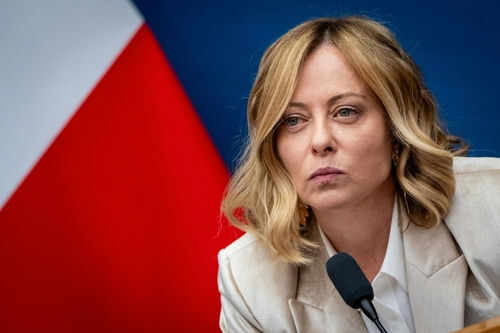 Person speaking at a conference with flag background