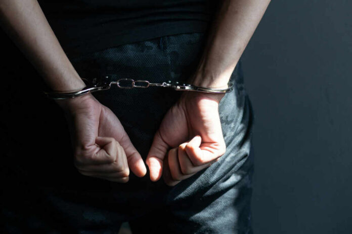 Person with hands cuffed behind back in handcuffs