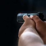 Person holding a black handgun in firing position