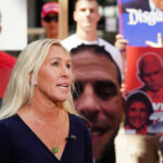 Greene Drops Bombshell: Lawler’s Anti-Trump Past Woman speaking with people holding political signs background