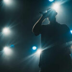 Silhouette of a musician performing on stage with bright lights