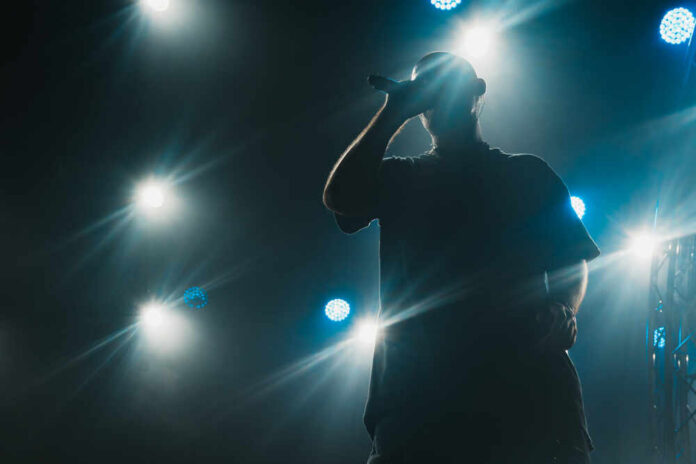 Silhouette of a musician performing on stage with bright lights