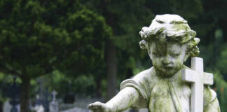 Weathered angel statue holding a cross in a cemetery