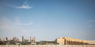 An industrial site with large structures and machinery under a clear blue sky