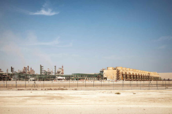 An industrial site with large structures and machinery under a clear blue sky