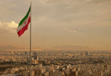 Iran’s Internet Blackout – A Nation Silenced Iranian flag waving over a city skyline with mountains in the background