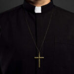 Clerical shirt with a cross necklace against a dark background
