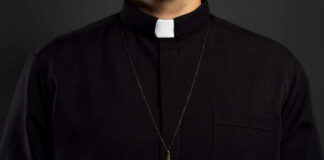 Clerical shirt with a cross necklace against a dark background