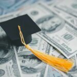 A graduation cap placed on a pile of hundred dollar bills