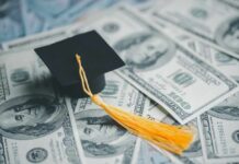 A graduation cap placed on a pile of hundred dollar bills