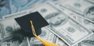 A graduation cap placed on a pile of hundred dollar bills