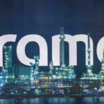 Illuminated oil refinery with the word 'Aramco' prominently displayed