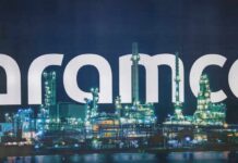 Illuminated oil refinery with the word 'Aramco' prominently displayed