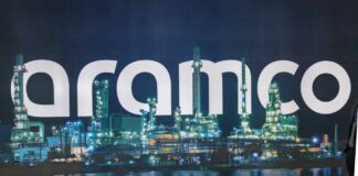 Illuminated oil refinery with the word 'Aramco' prominently displayed