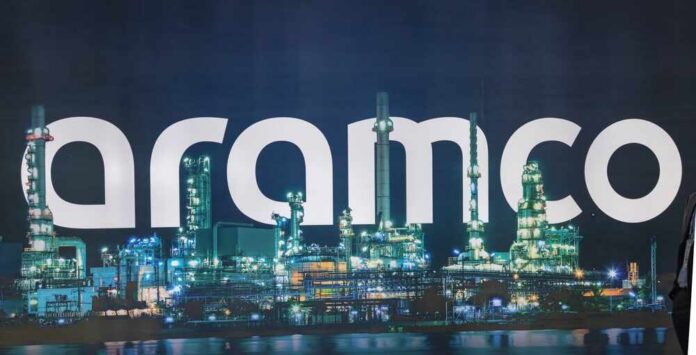 shutterstock_2438922083.jpg Illuminated oil refinery with the word 'Aramco' prominently displayed