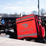 Trump’s No Tax on Tips: Game-Changer for Gig Workers A motorcycle with a bright red Doordash delivery bag parked in an urban area