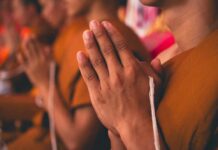 Monks with hands clasped in prayer during a ceremony