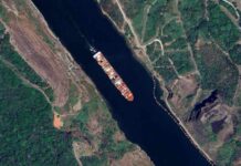 China WEAPONIZES Trade—Panama Ships Held Hostage Aerial view of a cargo ship navigating through a waterway surrounded by greenery