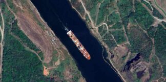 Aerial view of a cargo ship navigating through a waterway surrounded by greenery