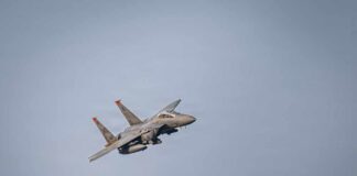 A military fighter jet performing an aerial maneuver against a clear sky