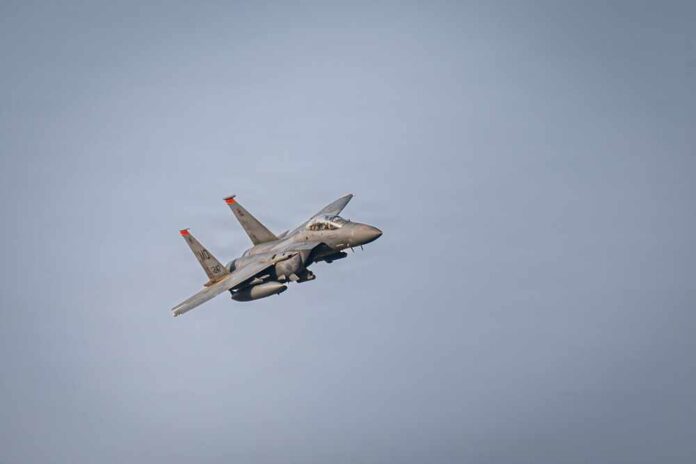 shutterstock_2716689565.jpg A military fighter jet performing an aerial maneuver against a clear sky