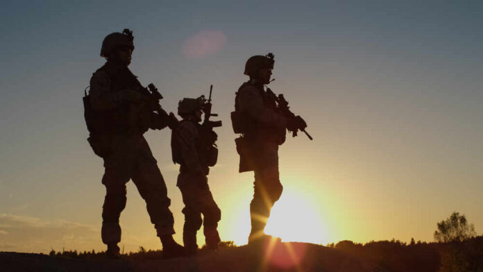 Silhouetted soldiers standing against a sunset