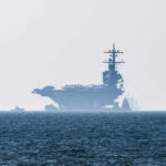 Navy SURROUNDS Iran—Catastrophe Brewing An aircraft carrier partially obscured by fog on the ocean
